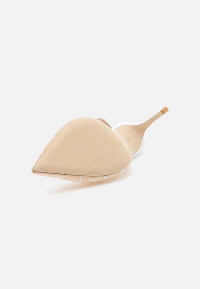 Chaussure à talon haut beige vue de la semelle, montrant un bout pointu, un talon aiguille fin et un motif texturé sur le côté.
