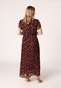 Maxikleid aus durchsichtigem Stoff mit floralem Druck. Es hat kurze Ärmel, ein plissiertes Design und eine taillierte Taille. Bunte Blumen auf schwarzem Hintergrund.