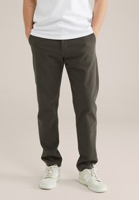 Donkergroene, rechte broek van een katoenmix, met zijzakken en een gladde textuur, gecombineerd met witte sneakers.
