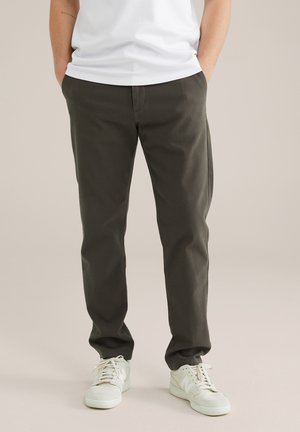 Dunkelgrüne, gerade geschnittene Hosen aus einem Baumwollmischgewebe mit Seitentaschen und glatter Textur, kombiniert mit weißen Sneakers.