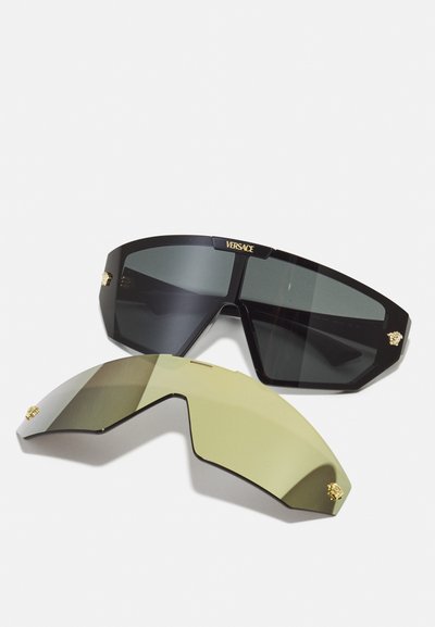 Versace sunglasses featuring a black plastic frame with dark lenses and gold accents. Includes a detachable light green lens.