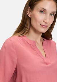 Rosa, struktureret bluse med en subtil V-udskæring og ærmer med manchetter. Lavet af letvægtsstof, med en afslappet pasform.