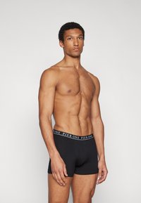 Boxers noirs avec un design ajusté, dotés d'une taille élastique avec le logo "PIER ONE". Texture lisse, style minimaliste.
