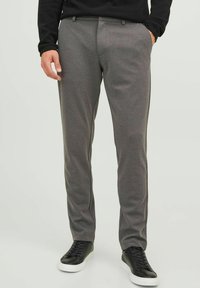 Gray trousers made of soft fabric, featuring a slim fit design with a flat front, front pockets, and worn with black sneakers.