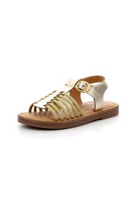 Sandales à lanières avec des finitions dorées et métalliques, dotées d'une semelle plate, d'un design à bout ouvert et d'une fermeture à boucle réglable au niveau de la cheville.