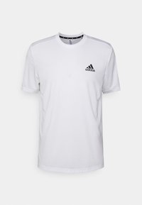 Valkoinen lyhythihainen t-paita, joka on valmistettu sileästä kankaasta ja jossa on musta Adidas-logo vasemmassa rinnassa sekä kontrastiväriä olkalaidoissa.