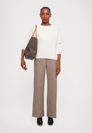 Pulover alb din tricot, pantaloni largi cu model houndstooth maro, cizme negre cu toc și o geantă tote maro cu model, având accente din piele.