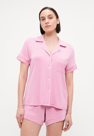 Pink pajama set in soft fabric, featuring a collared short-sleeve top with a pocket and coordinating shorts with piped accents.