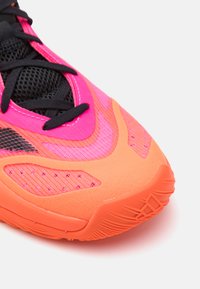 Scarpa sportiva con un design arancione e rosa brillante, tomaia in rete, lacci neri e suola testurizzata per una presa migliore. Presenta una forma affusolata.