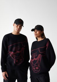  svarte strikkede gensere med et stort burgunder okse-motiv foran, kombinert med svarte caps som viser et lignende okse-logo.
