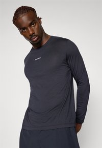 Langärmliges navy-blaues Hemd aus Stretchstoff, mit Rundhalsausschnitt, dezentem Branding auf der Brust und einer glatten, körperbetonten Textur.