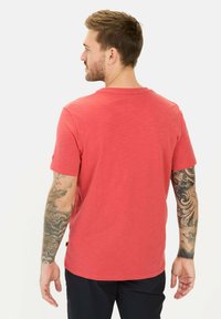 Rød bomulds t-shirt med kortærmer, rund hals og en afslappet pasform. Har en glat tekstur og et mærke nær sømmen.