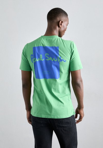 T-shirt en coton vert avec un design carré bleu portant le texte "Paul Smith" en blanc et en vert. Manches courtes, col rond et coupe décontractée.