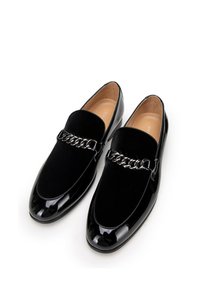 Zwarte loafers met een glanzende lakleren neus en een zachte fluwelen bovenkant. Kenmerkt zich door een decoratieve kettingaccent over de wreef.