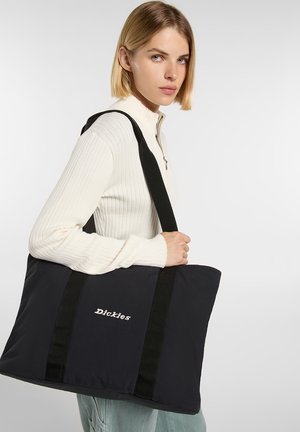 Sac fourre-tout noir avec des anses épaisses noires, fabriqué en tissu lisse. Présente un logo "Dickies" blanc sur le devant, de forme rectangulaire, avec une texture douce.