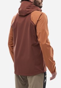 Veste imperméable de couleur rouge foncé et beige, dotée d'une capuche, de manches longues et d'une texture lisse ; conçue pour une activité de plein air et le confort.