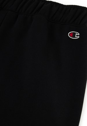 Pantalones de chándal negros con cintura elástica, que presentan un pequeño logo bordado en rojo y blanco, fabricados en material de algodón suave.