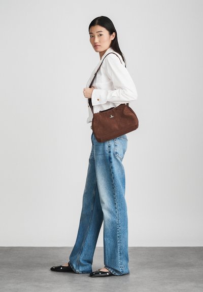 Ruda zomšinė rankinė su išlenkto pavidalo, trumpa reguliuojama petneša ir mažos logotipo akcentas. Sujungta su mėlynomis plačiomis džinsomis ir baltu marškinėliu.