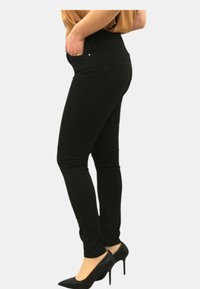 Jeans skinny neri con una trama liscia, vita alta e cuciture sottili. Abbinati a scarpe con tacco alto nere e un top beige.