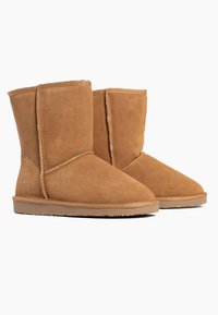 Suede ankle boots in tan color with a rounded toe and stitched detailing. Flat rubber sole with light tread for traction.