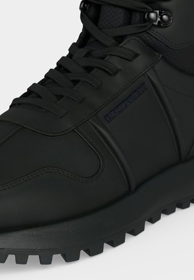 Μαύρο δερμάτινο και υφασμάτινο ψηλό sneaker με υφή στη σόλα και μαύρα κορδόνια, με ανάγλυφο λογότυπο Emporio Armani στο πλάι.