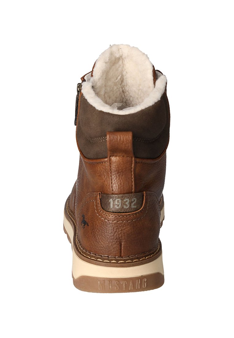 Braune Lederstiefel mit einer flauschigen weißen Fütterung, hohem Knödesel-Design, seitlichem Reißverschluss und geprägten Details. Verfügt über eine beige Sohle und ein Logo.