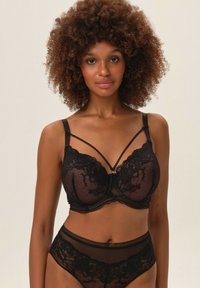 Czarny zestaw bielizny składający się z koronkowego biustonosza z wyściełanymi miseczkami, szczegółowo zdobionymi ramiączkami oraz przezroczystą wstawką. Majtki z wysokim stanem mają dopasowany koronkowy akcent.