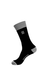 Chaussette noire avec un revers côtelé gris, des accents gris au niveau des orteils et du talon, et un texte de marque blanc "SERGE BLANCO" près de la cheville. Texture de tissu lisse.