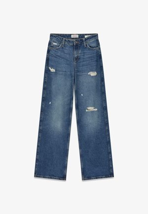 Weit geschnittene blaue Jeans aus Denim mit ausgewaschenen Bereichen und sichtbaren abgenutzten Stellen. Mit dekorativen Steppnähten und einem Reißverschluss vorne.