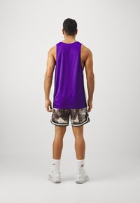 Lilla ilmaõlaga tank top, must-valged sääreosa lühikesed püksid, valged sport sokid ja valged sussid. Vaade selg ees mehe figuurile.
