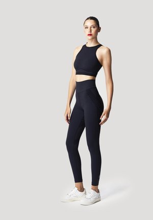 Marinefarbener Sport-BH und passende High-Waist-Leggings aus elastischem Material, mit strukturierten Akzenten und einem eleganten, figurschmeichelnden Design.