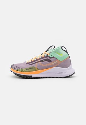 Jasnofioletowy i zielony but do biegania po szlakach Nike z pomarańczowymi sznurówkami, białą podeszwą, materiałem Gore-Tex i czarnym bieżnikiem, pokazany z boku.
