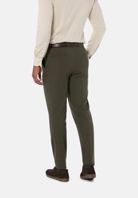 Donkergroene op maat gemaakte broek van textuurstof, met een slim fit, zijzakken en een bijpassende riem. Draagt het met bruine schoenen.