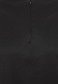 Schwarzer Stoff mit glatter Textur, der eine vertikale Naht und ein dezentes Reißverschlussdetail auf der Rückseite aufweist. Schlichtes und elegantes Design.