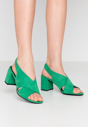 Grüne Wildleder-Absatzsandalen mit offener Zehenpartie, Slingback-Design und überkreuzten Vorderriemen. Klobiger, quadratischer Absatz für Stabilität. Texturierte Oberfläche.