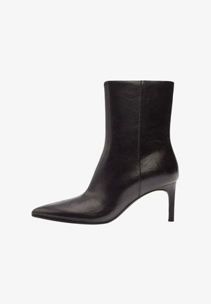 Črni usnjeni gležnjar z ostro konico, vitkim peto, gladko teksturo in minimalističnim dizajnom; ima enoten stranski profil brez šivov.