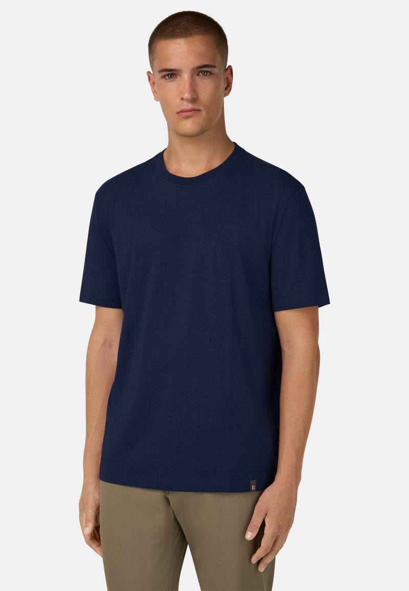 Tmavě modré tričko s krátkým rukávem vyrobené z bavlny, s kulatým výstřihem a malou etiketou na dolním levém boku. Hladká textura a volný střih.