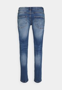 Jeans in denim blu con vestibilità slim, dotati di tasche posteriori, leggera scoloritura e una superficie liscia. L'orlo è leggermente risvoltato alle caviglie.