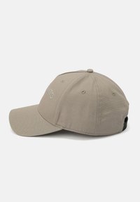 Gorra de béisbol caqui con visera curva, seis paneles, agujeros de ventilación y correa trasera ajustable. Presenta texto bordado en la parte frontal.