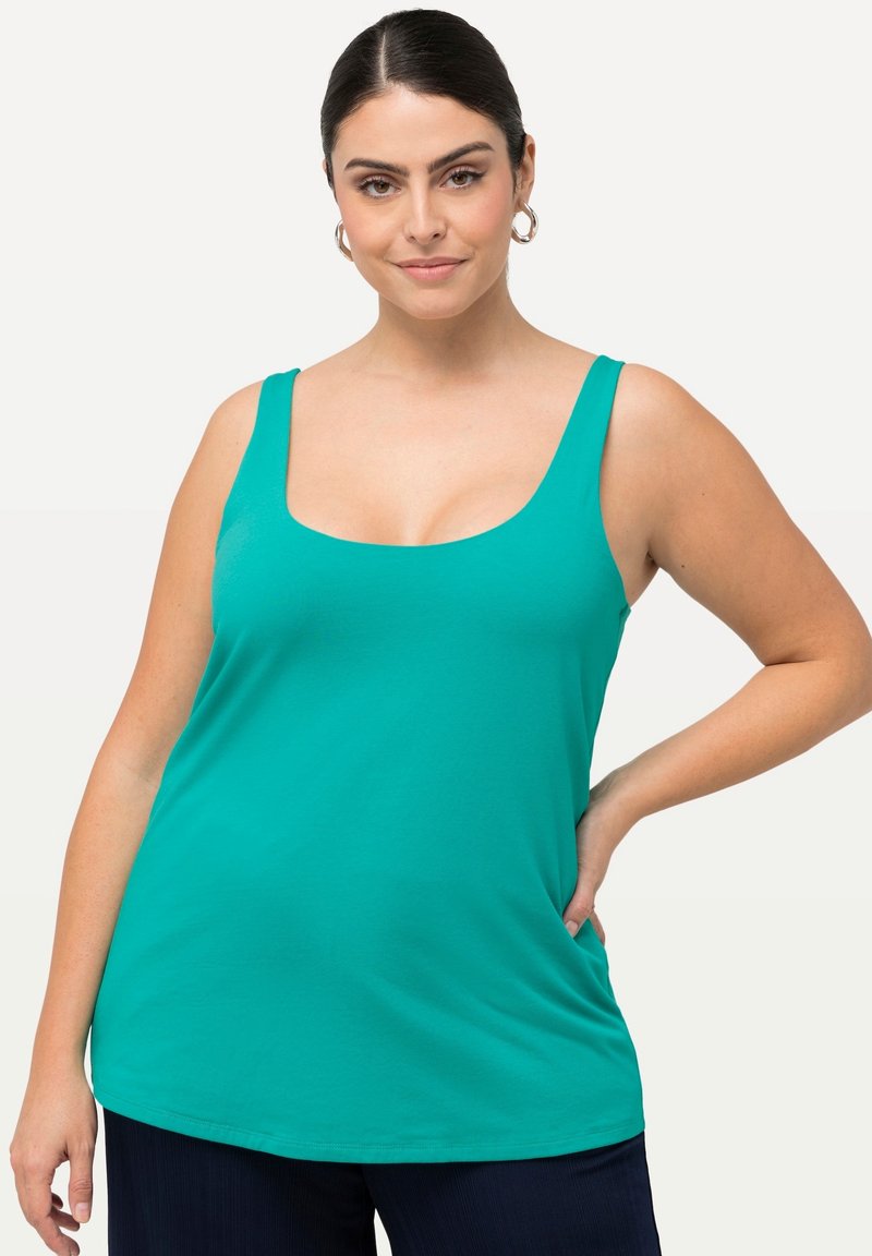 Una blusa sin mangas en color turquesa con un amplio escote redondeado. Está confeccionada con una tela suave, presenta un ajuste relajado y un dobladillo ligeramente curvado.