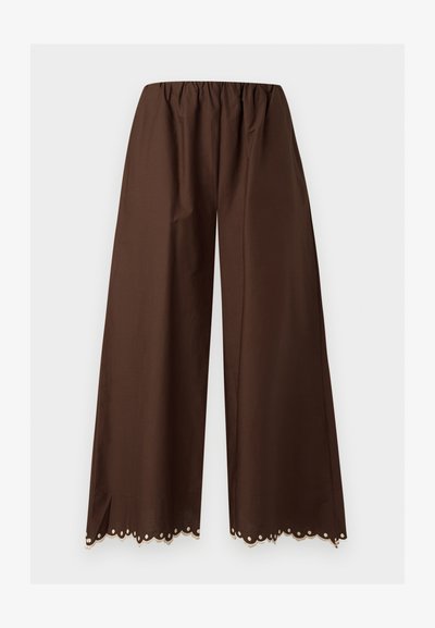 Καφέ παντελόνι με φαρδιά μπατζάκια, ελαστική μέση και διακοσμητικό δαντελένιο τελείωμα με κυματιστά σχέδια στο κάτω μέρος, πάνω σε λευκό φόντο.