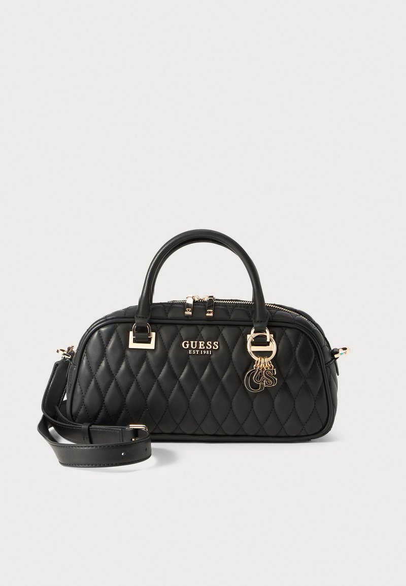 Black quilted handbag with gold hardware, dual handles, and detachable shoulder strap. Features brand logo and decorative charm detail.