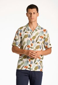 Kortærmet skjorte med knaplukning, på hvid baggrund, med et tropisk print af ananas, papayaer og grønne blade.