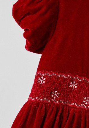 Rotes Samtkleid mit puffärmeln, gesmoktem Oberteil mit silberner Schneeflockenstickerei und einer gerafften Rockpartie.