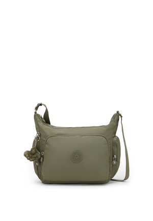 Borsa a tracolla verde oliva con più scomparti con cerniera e un piccolo portachiavi a forma di scimmietta di peluche attaccato al lato.
