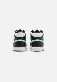 Wysokie sneakersy z czarną skórzaną cholewką i zielonymi akcentami, białą podeszwą środkową oraz teksturowaną podeszwą. Widok z tyłu pokazuje detale logo.