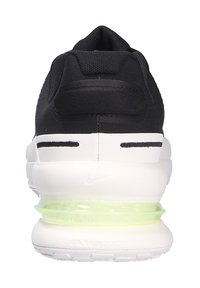 Scarpa sportiva nera con una tomaia in rete testurizzata, suola intermedia bianca e unità ad aria neon verde visibile. Presenta un colletto imbottito e piccoli dettagli di branding.