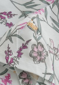 Hvidt stof med pink, lilla og gule blomster mønstre samt grønne blade; blød tekstur, synlige syninger.