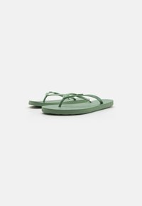 Grønne gummisandaler med en tekstureret sål, der har to smalle stropper, som krydser over foden og giver et minimalistisk design.