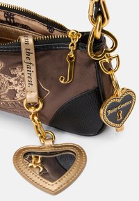 Brun og sort taske med guldhardware, et hjerteformet spejl og en hængelås charm. Broderede detaljer og lynlås lukning.